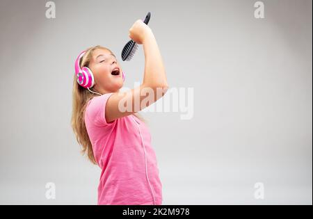 Cute young girl singing along to her music Stock Photo