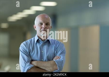 Senior businessman with folded arms indoors Stock Photo