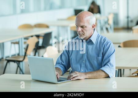 Businessman working on a laptop in a canteen Stock Photo