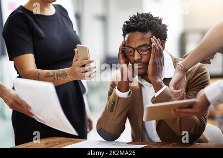 When stress gets the best of you. Cropped shot of a stressed out businessman surrounded by colleagues needing help in an office. Stock Photo
