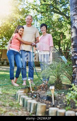 One big happy family. Portrait of a family watering a garden with a hose. Stock Photo