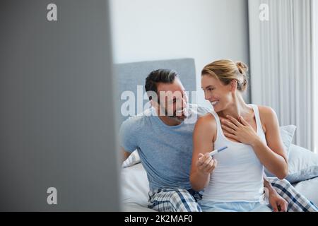 This moment is finally happening. Cropped shot of a middle aged couple looking happy after taking a home pregnancy test in their bedroom. Stock Photo