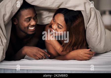 Undercover lovers. Cropped shot of an affectionate young couple lying under the covers on their bed at home. Stock Photo