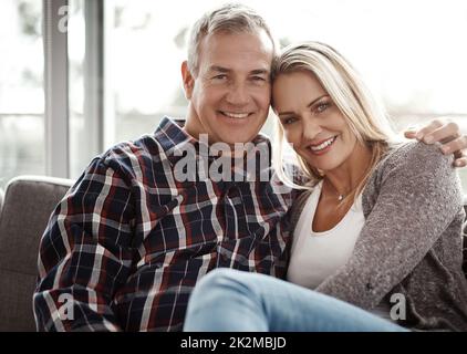 Whats the weekend without quality time. Shot of an affectionate mature couple relaxing together on the sofa at home. Stock Photo