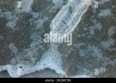 Nature is our responsibilty. Shot of a bottle laying on the beach. Stock Photo