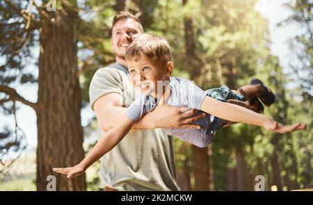 Flying with dad. Cropped shot of a handsome young man playing with his adorable little son while camping in the woods. Stock Photo