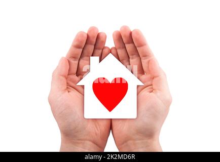 Paper house with red heart cutout in hands isolated on white background with clipping path. Stock Photo