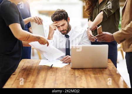 Im seriously so stressed out right now. Cropped shot of a stressed out businessman surrounded by colleagues needing help in an office. Stock Photo