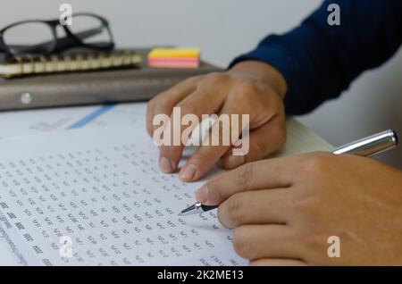 Man hand holding a pen and document paper work marketing financial plans Tax and business investment. Stock Photo