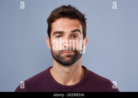 I cant be bothered. Studio shot of a handsome young man looking bored against a gray background. Stock Photo