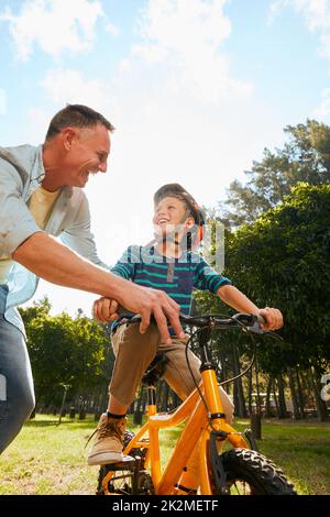 Dads got you. Shot of a father teaching his son how to ride a bicycle. Stock Photo