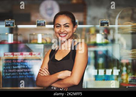Living that cafe life. Portrait of a young barista posing with her arms crossed in a coffee shot. Stock Photo