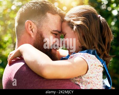 Solidifying strong father daughter bonds. Shot of an adorable little girl sharing an affectionate moment with her father outdoors. Stock Photo