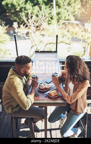 Good coffee, company and food, cant get any better. Cropped shot of a young couple in a coffee shop. Stock Photo