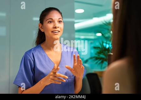 Explaining the ins and outs of medical cover. Shot of a young nurse discussing a procedure with her patient in the clinic. Stock Photo