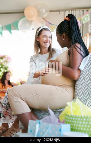 Do you think Id be able to feel them. Shot of two women relaxing during a baby shower. Stock Photo
