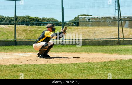 Hes ready to get a good catch. Full length shot of a young baseball player preparing to catch a ball during a match on the field. Stock Photo