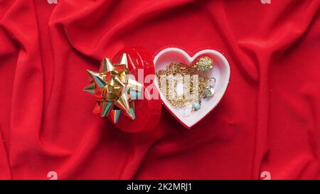 Close up of jewelry in heart shaped box on red satin Stock Photo