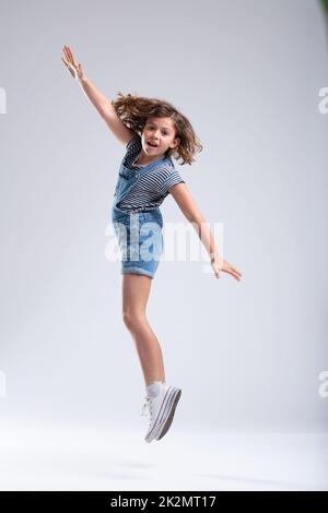 Young girl jumping in the air with extended arms Stock Photo