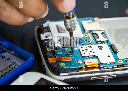 Technician repairing inside of mobile phone by soldering iron. Integrated Circuit. the concept of data, hardware, technology. Stock Photo