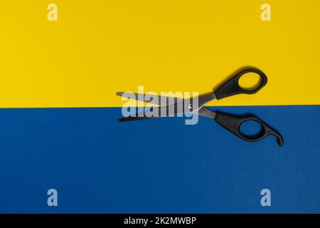 scissors on a blue and yellow background Stock Photo