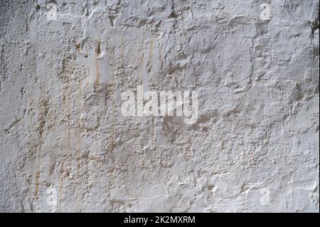 A old white painted wall with peeling paint and whitewash on an old building in Spain.  An abstract texture or background Stock Photo