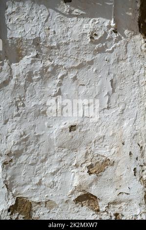 A old white painted wall with peeling paint and whitewash on an old building in Spain.  An abstract texture or background Stock Photo
