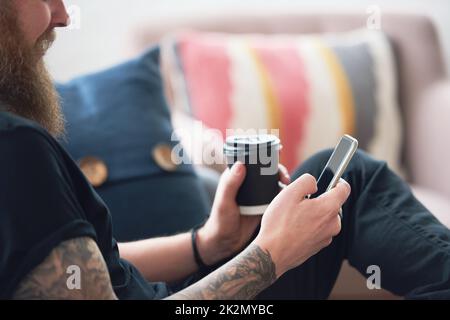 hipster man using smartphone browsing messages on social media texting on mobile phone holding coffee Stock Photo