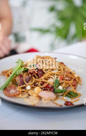 Spaghetti dried chili bacon, garlic, basil and garnish cheese in white plate Stock Photo