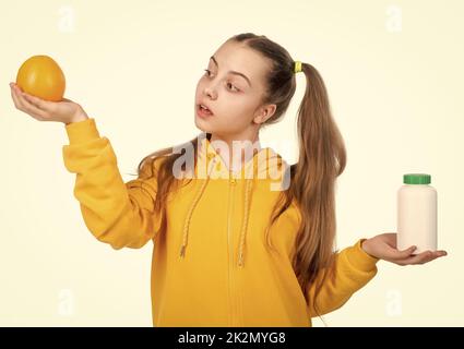 choice between natural products and pills. presenting vitamin product. child with orange pill. Stock Photo