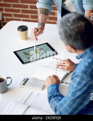 two businessmen using tablet computer discussing financial graph data on mobile touchscreen device in meeting Stock Photo