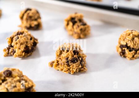 Scooping cookie dough with dough scoop into a baking sheet lined with  parchment paper to bake soft oatmeal raisin walnut cookies Stock Photo -  Alamy