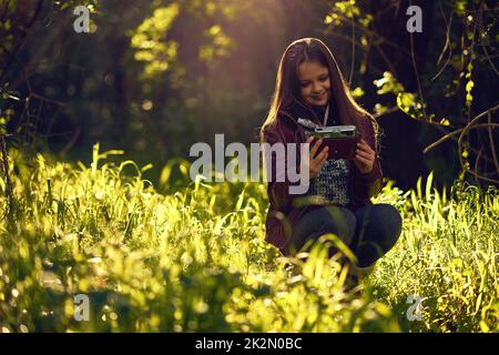 This is some great lighting for a selfie. Shot of a young girl taking a selfie with a vintage camera outdoors. Stock Photo