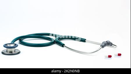 Stethoscope and red-white capsule pills on doctor table or nurse desk. Health checkup. Diagnostic medical tool for patient diagnosis. Drug induced cardiotoxicity. Heart or cardiac toxicity drug. Stock Photo