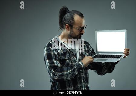 Hipster man holding a laptop and looking at its green screen Stock Photo