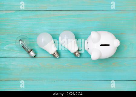 Piggy bank and  light bulbs on blue wooden background Stock Photo