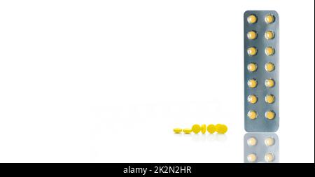 Yellow film coated tablets pills in blister packs and group of round yellow tablets pills on white background. Pharmacy horizontal web banner. Prescription drugs. Pharmacy products. Health care topics. Stock Photo