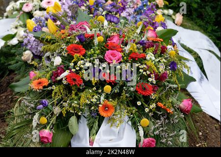 many colorful flowers on a grave after a funeral Stock Photo