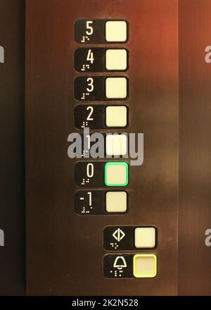 Elevator buttons, number 0 in green, blind, text in Braille alphabet under numbers, for blind disabled people. Stock Photo