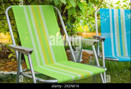 Two garden folding chairs stand in the shade under a tree on a hot summer day in the garden, close-up Stock Photo