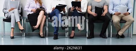 Row Of Candidates Sitting On Chair For Job Interview Stock Photo