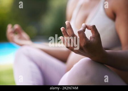Yoga teaches you how to breathe deeply and consciously relax. Cropped shot of a pregnant woman meditating while sitting outside. Stock Photo