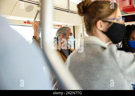 Senior male passenger in face mask riding public bus