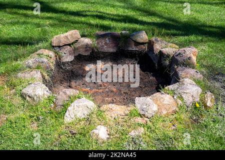 rustic stone circle fire pit in sunny grass background Stock Photo