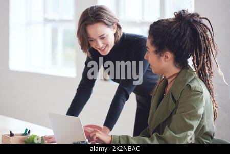 Two business women students using laptop computer team leader woman helping colleague with project sharing ideas Stock Photo