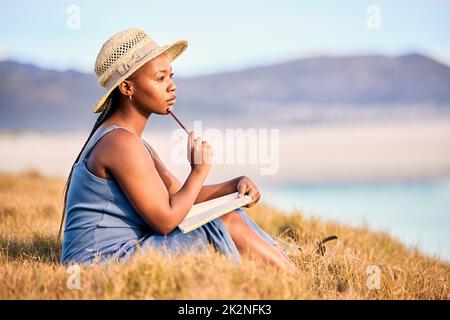 Drowning dialogues. Shot of a young woman writing in her journal at the beach. Stock Photo