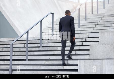 Walking up to success. Shot of an unrecognizable businessman walking up stairs in the city. Stock Photo