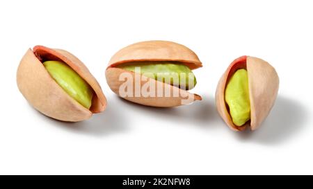 Three Turkish red pistachios (Antep), isolated on white background. Peeled green nuts visible inside. Stock Photo