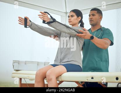 Hold for me.... Cropped shot of a handsome young male physiotherapist working on a female patient outside. Stock Photo