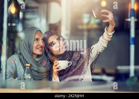 Whats better than coffee A best friend. Shot of two women taking selfies with a mobile phone in a cafe. Stock Photo